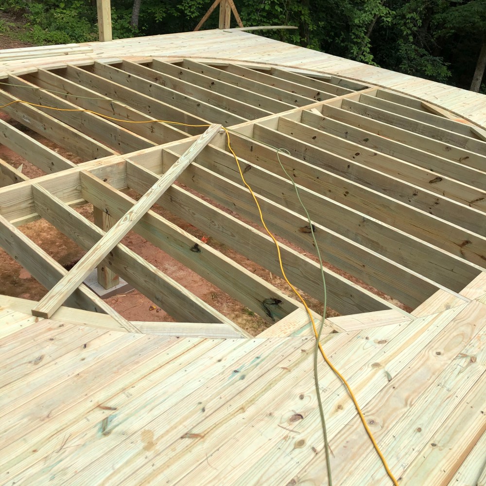 Wooden deck in progress with hole jig and electric cords.